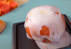 Z wydrążonej dyni wylatuje piana, która jest następstwem reakcji sody, octu i płynu do naczyń