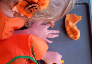 Dzieci ugniatają pomarańczową ciastolinę