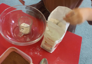 Dziewczynka wsypuje mąkę do miski