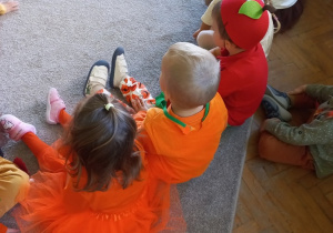 Dzieci siedzą na dywanie i słuchają jesiennych zagadek