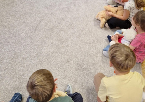 Dzieci siedzą w kole i opowiadają o swoich misiach