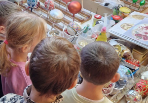 Dzieci obserwują technikę ozdabiania bombek
