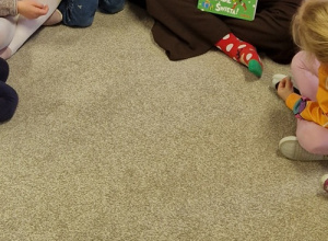 Dzieci siedzą na dywanie i słuchają bajki