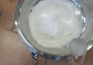 Dziecko wlewa wodę do miski z mąką