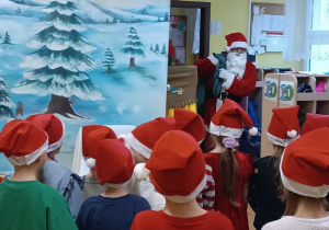 Dzieci wpatrują się w Świętego Mikołaja niosącego worek z podarunkami.