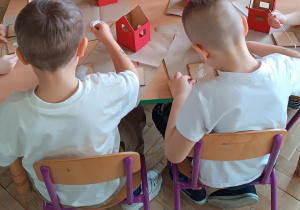 Dzieci sklejają elementy domku.