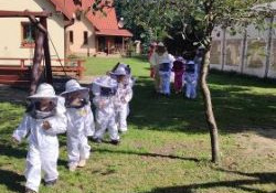 Grupa dzieci w kombinezonach idzie po trawie