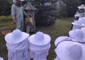 Pszczelarz pokazuje dzieciom ul wykonany z pnia drzewa