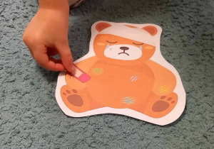 Dziecko przykleja plaster w odpowiednim kolorze na ranę sylwety Misia