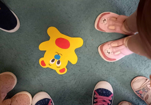 Dzieci podczas zabawy ruchowej odnalazły żółtego misia leżącego na dywanie