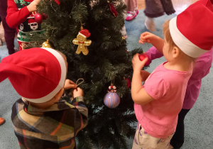 Dzieci ozdabiają drzewko przyniesionymi ozdobami