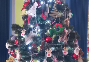Choinka ubrana w lampki i światełka stoi na szafce w naszej grupie