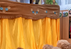 Dzieci siedzą przed scena i oglądają spektakl pt. "Kruszynka"