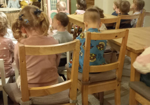 Dzieci siedzą na niskich krzesełkach i czekają na przedstawienie