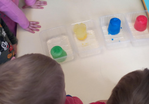 Na stole leżą kolorowe kostki lodu, które zamarzły nocą na mrozie