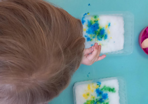 Dzieci barwią śnieg przy użyciu kolorowej wody i pipet