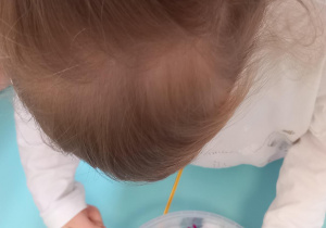 Dziewczynka barwi śnieg mieszając go z różową bibułą