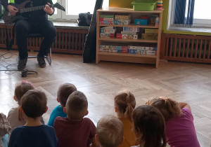 Dzieci z uwagą słuchają kolejnych dźwięków gitary