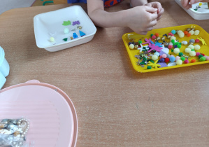 Dziecko wybiera z tacki pomponiki.