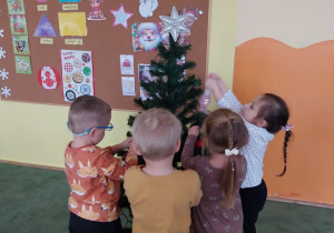 dzieci zawieszają ozdoby na choinkę