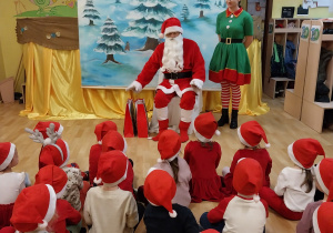 dzieci siedzą i słuchają Świętego Mikołaja