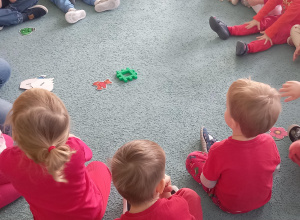 Dzieci siedzą w kole i wspólnie z panią wykonują zadanie