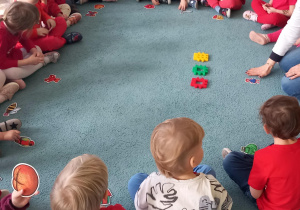 Dzieci siedzą w kole i wspólnie z panią wykonują zadanie
