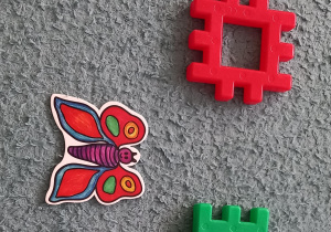 Na dywanie leży ilustracja motyla i klocki przedstawiające podział na sylaby