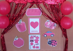 Na tablicy przywieszone są obrazki przedstawiające przedmioty w kolorze czerwonym