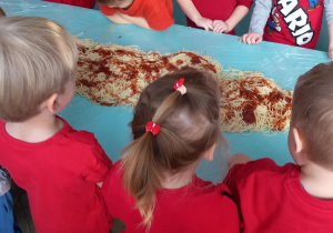 Na tablicy przywieszone są obrazki przedstawiające przedmioty w kolorze czerwonym