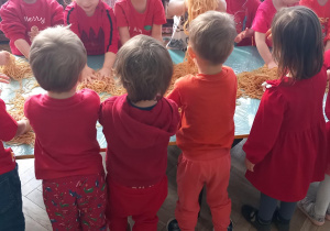 Dzieci stoją przy stoliku, na którym leży makaron polany keczupem