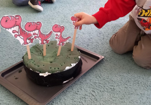 Chłopiec układa dinozaury od największego do najmniejszego