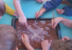 Dzieci z wielkim zapałem odszukują pędzelkami szczątków dinozaura