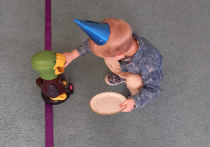 Chłopiec kuca i karmi zabawkową kaczkę