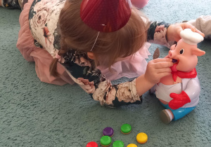 Dziewczynka karmi zabawkowego prosiaczka