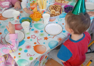 Dzieci rozmawiają przy stole i częstują się smakołykami