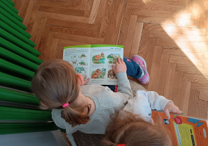 2 dziewczynki oglądają książki o dinozaurach