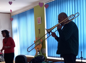 Dzieci słuchają i patrzą się na Pana, który gra na puzonie