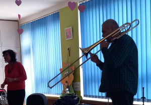 Dzieci słuchają i patrzą się na Pana, który gra na puzonie