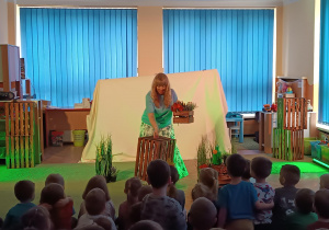 Aktorka układa skrzynie z kwiatami.