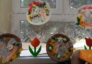 Ozdoba z papierowego talerzyka na którym naklejony jest zając, sztuczne kwiaty