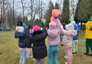 Dzieci w jednorazowych rękawiczkach, trzymając worki pozują do zdjęcia