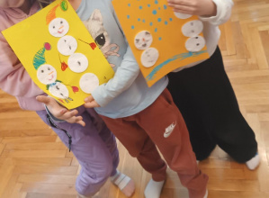 Dzieci trzymają pracę plastyczną z wyklejonymi bałwankami.