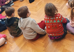 Dzieci uważnie słuchają pani bibliotekarki, która prowadzi zajęcia