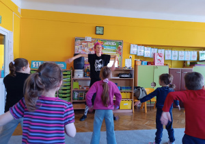 Dzieci naśladują ruchy instruktorki tańca.