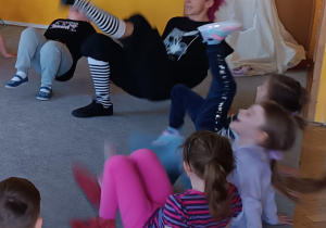 Dzieci naśladują ruchy instruktorki tańca.