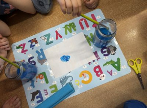 Dzieci malują na kartce niebieską farbą