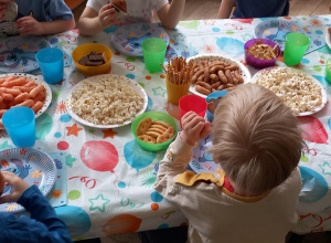 Dzieci siedzą przy stolikach i jedzą łakocie