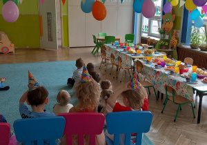 Solenizanci siedzą na kolorowych krzesełkach