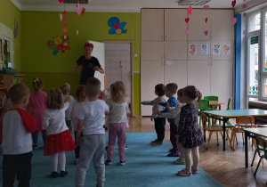 Dzieci stoją naprzeciwko prowadzącej i naśladują jej ruchy